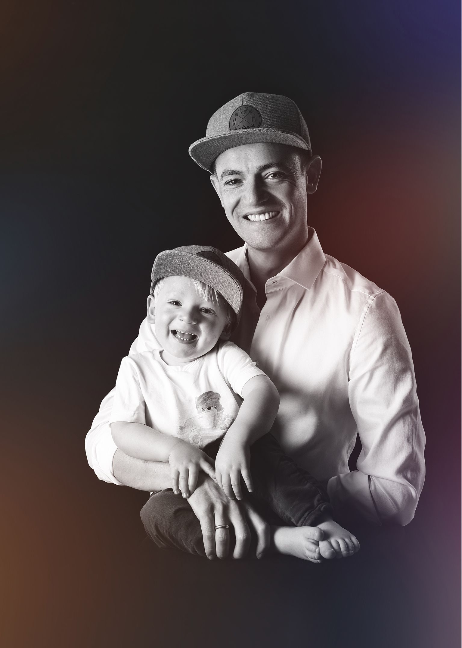 Schwarz-weiß-Porträt eines jungen Mannes mit Hut, der freundlich lächelt.