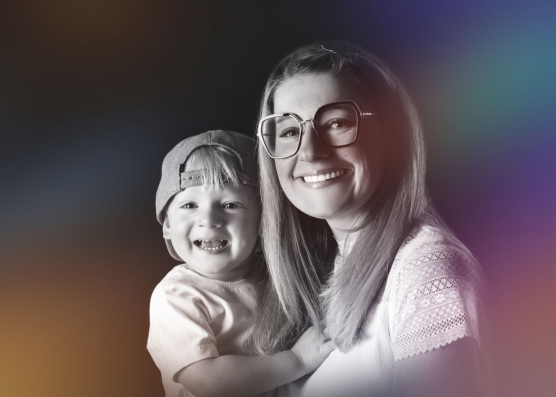 Mutter und Kind in schwarz-weiß, beide lächelnd, mit weicher Beleuchtung.