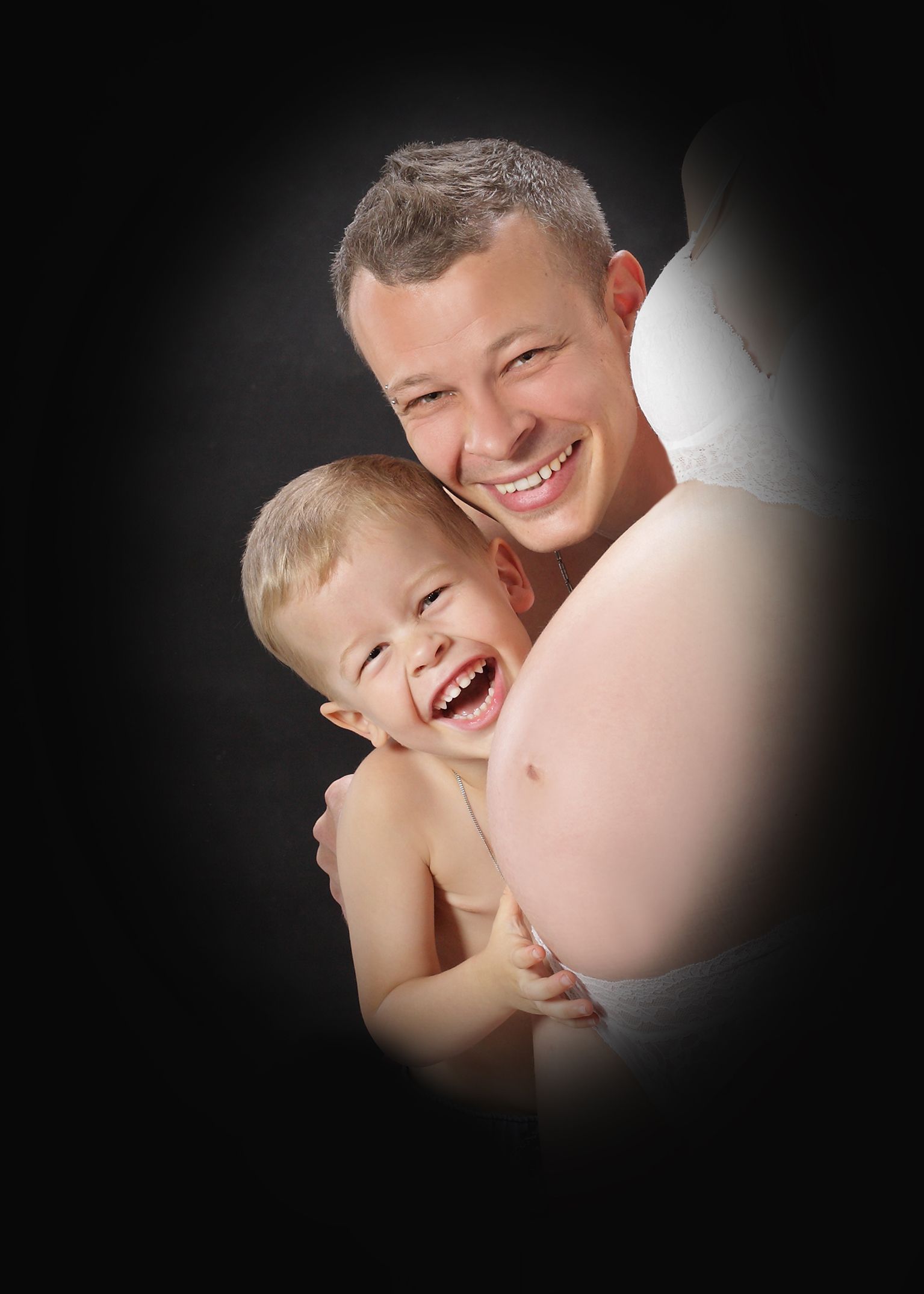 Lächelnder Mann in einem dunklen Studio, sanft ausgeleuchtet.