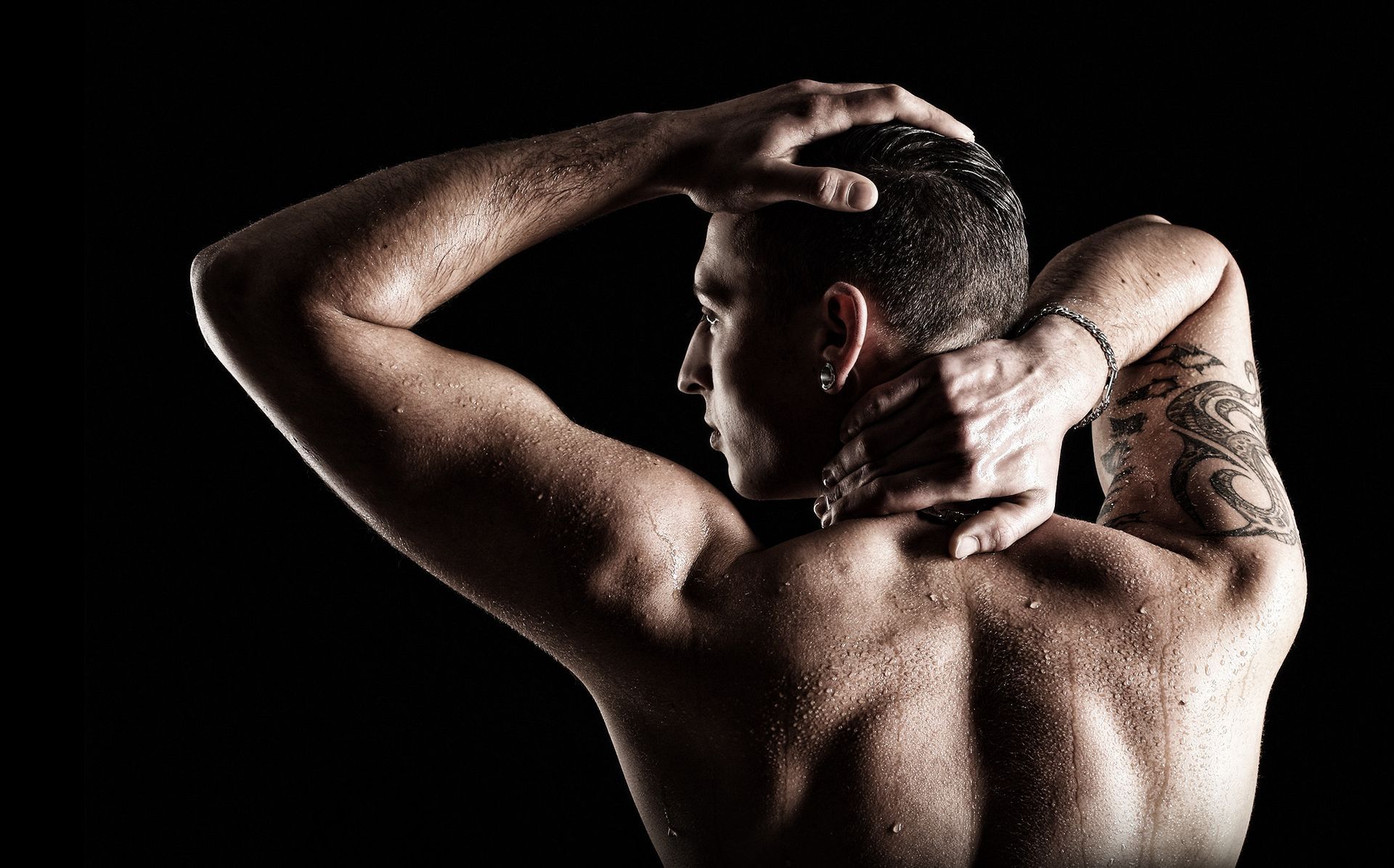 Stark kontrastreiche Aufnahme eines Mannes mit nassem Oberkörper, der sich seitlich abwendet.