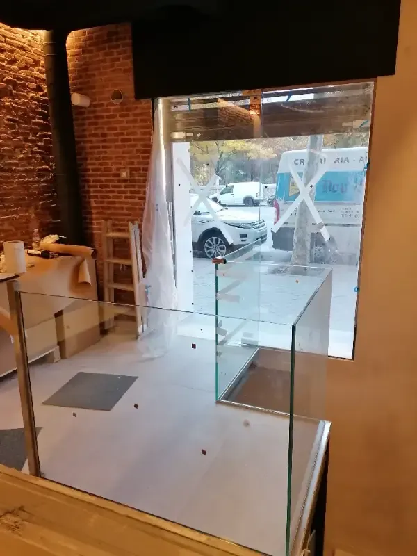 Una vitrina de cristal se encuentra sobre un mostrador dentro de una habitación con una pared de ladrillo visto