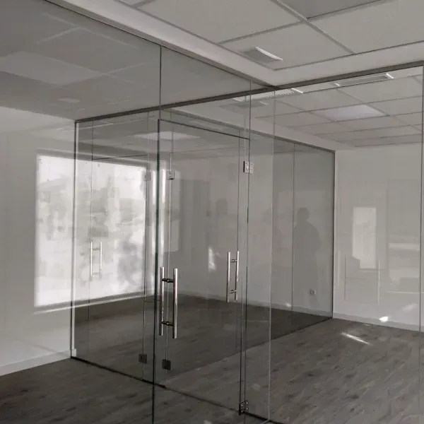 Una moderna sala de conferencias con paredes de cristal, puerta de cristal, tiradores metálicos y suelo de imitación madera.