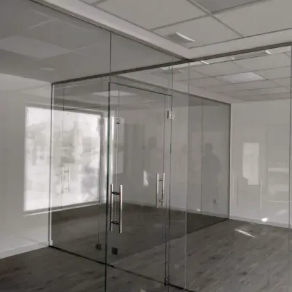 Una moderna sala de conferencias con paredes de cristal, puerta de cristal, tiradores metálicos y suelo de imitación madera.
