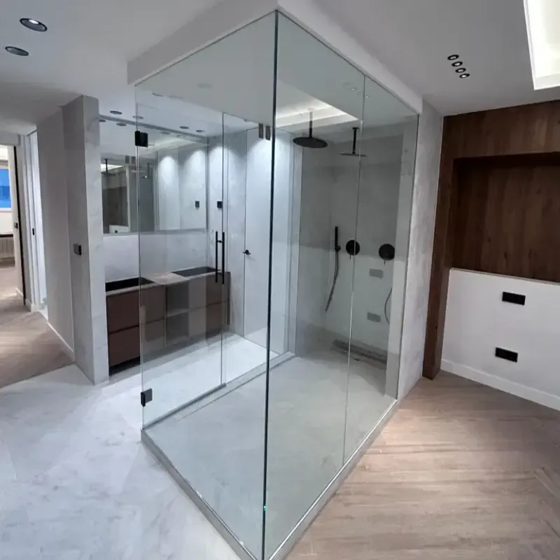 Una moderna cabina de ducha de cristal en un baño con detalles en madera y blanco, junto a un espejo de tocador.