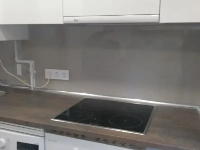 Encimera de cocina moderna con placa de inducción de vidrio negro y protector contra salpicaduras de vidrio gris.