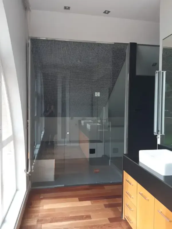 Un baño que cuenta con una amplia ducha a ras de suelo con mampara de cristal, paredes revestidas de azulejos oscuros