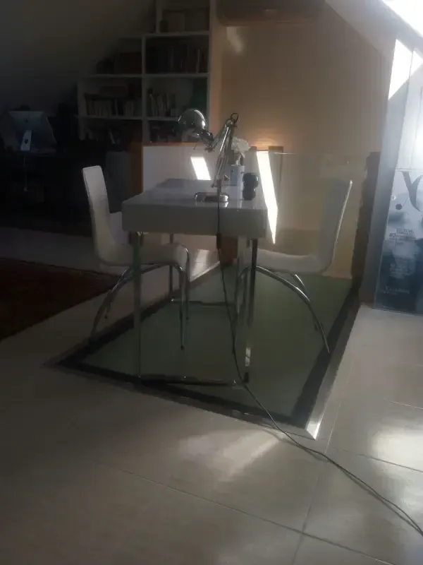 Un escritorio blanco y dos sillas se encuentran sobre una alfombra rectangular verde en una habitación