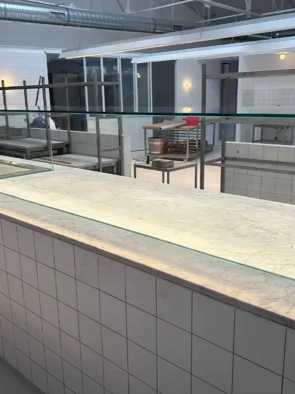 Vista de un mostrador de servicio de cocina comercial y una mampara protectora de vidrio.