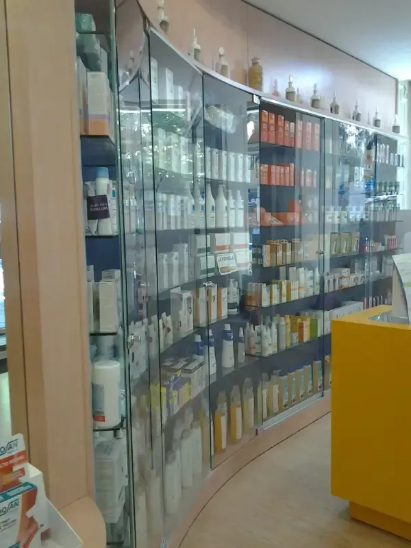Estanterías de una farmacia o tienda repletas de diversos productos exhibidos tras vitrinas de cristal.