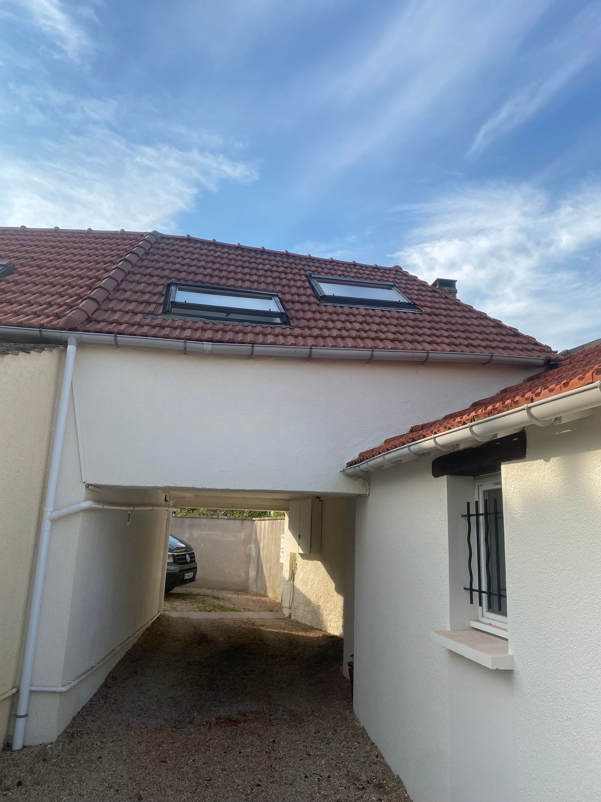 Une étroite allée de gravier mène sous une partie d'une maison.