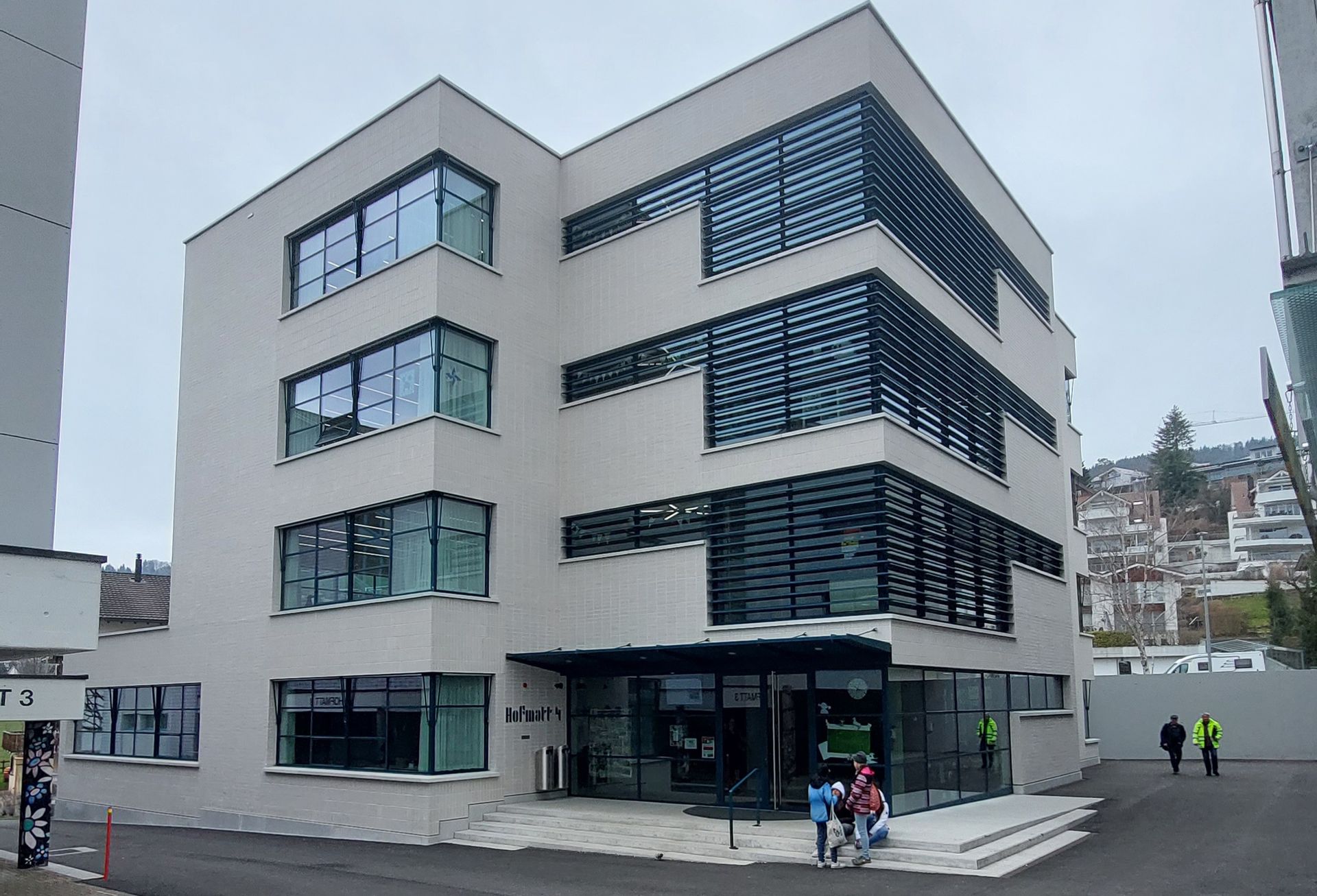 Ein Gebäude mit vielen Fenstern und Menschen, die davor gehen