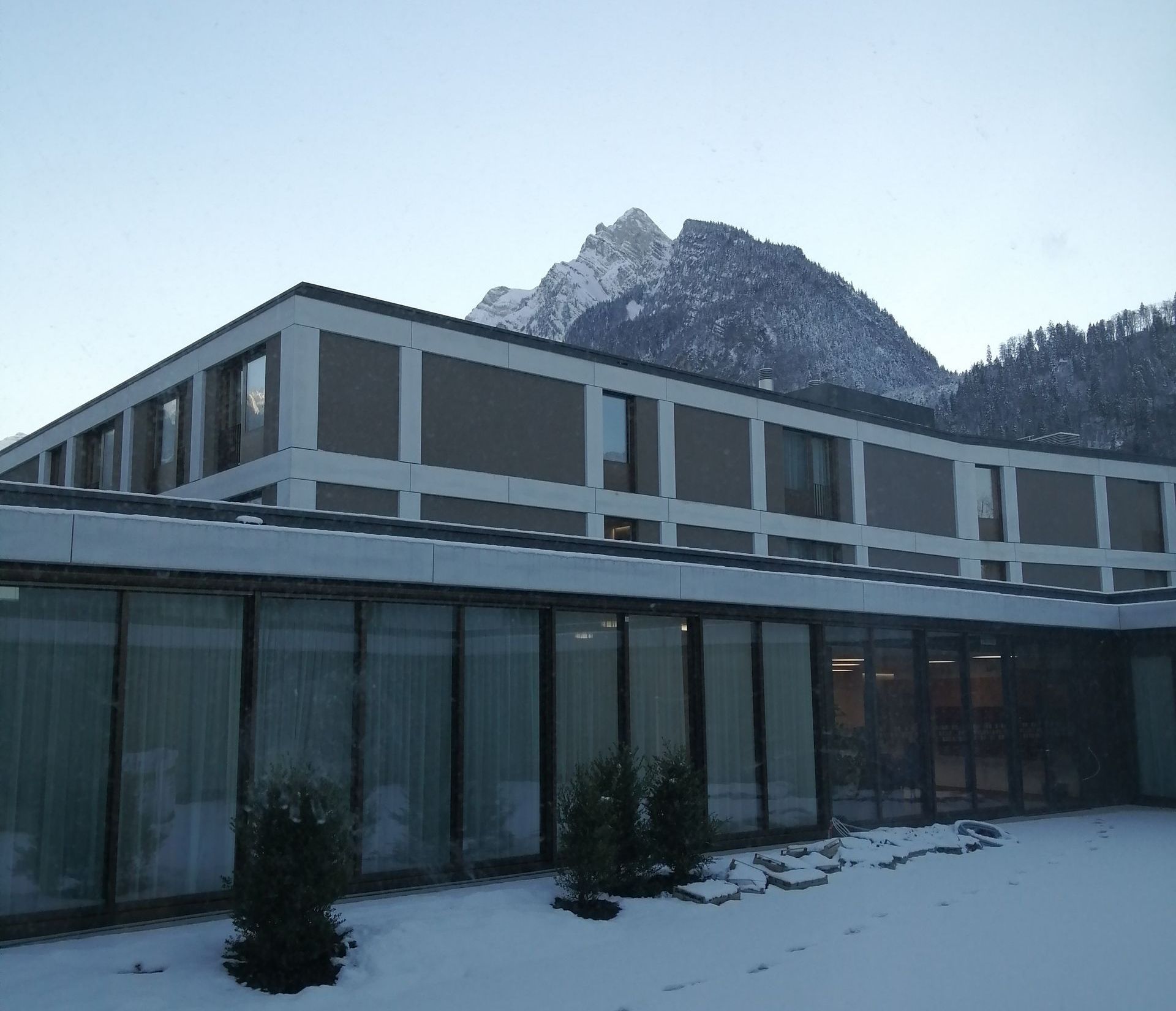 An einem sonnigen Tag parkt ein LKW vor einem großen Gebäude.