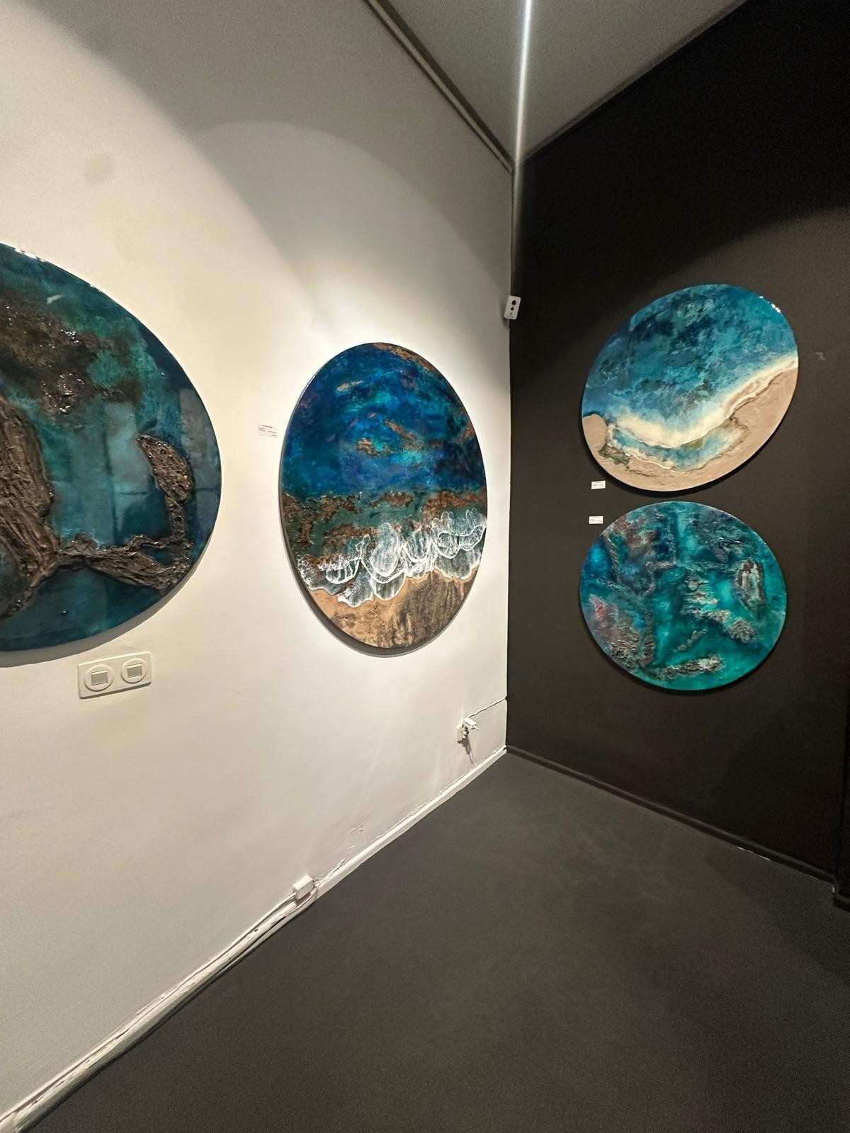 Rincón de galería con tres obras de arte abstractas redondas de color azul 