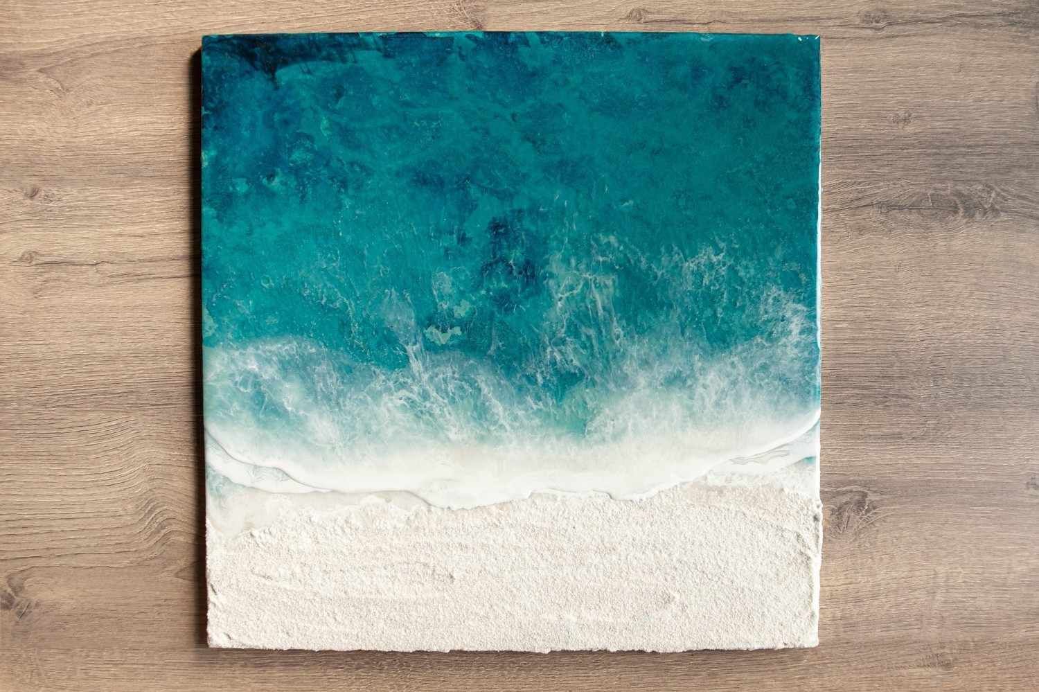 Pintura abstracta en turquesa y blanco sobre una superficie de madera