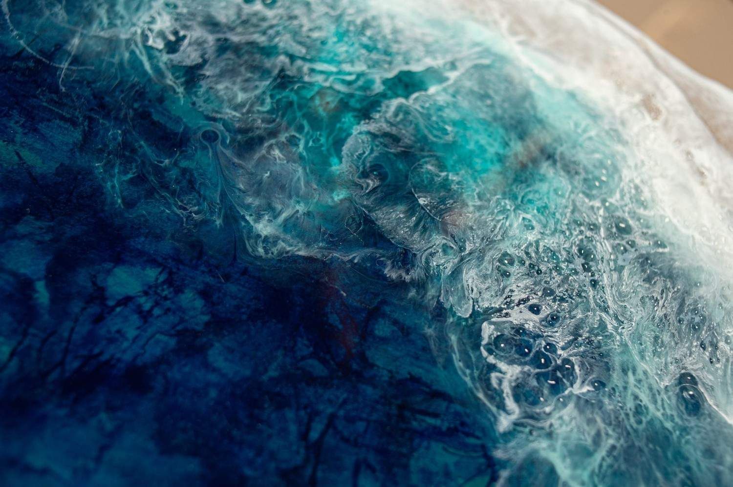 Vista aérea abstracta de olas oceánicas azules y espuma blanca arremolinándose cerca de la costa.