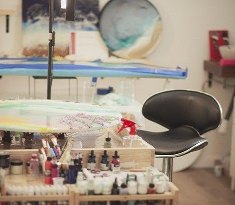 Estudio de tatuajes con una silla negra, botes de tinta y un brazo tatuado en primer plano.