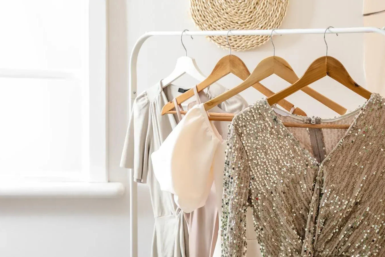 Perchero con tres vestidos y un top; color tostado, beige y plateado.