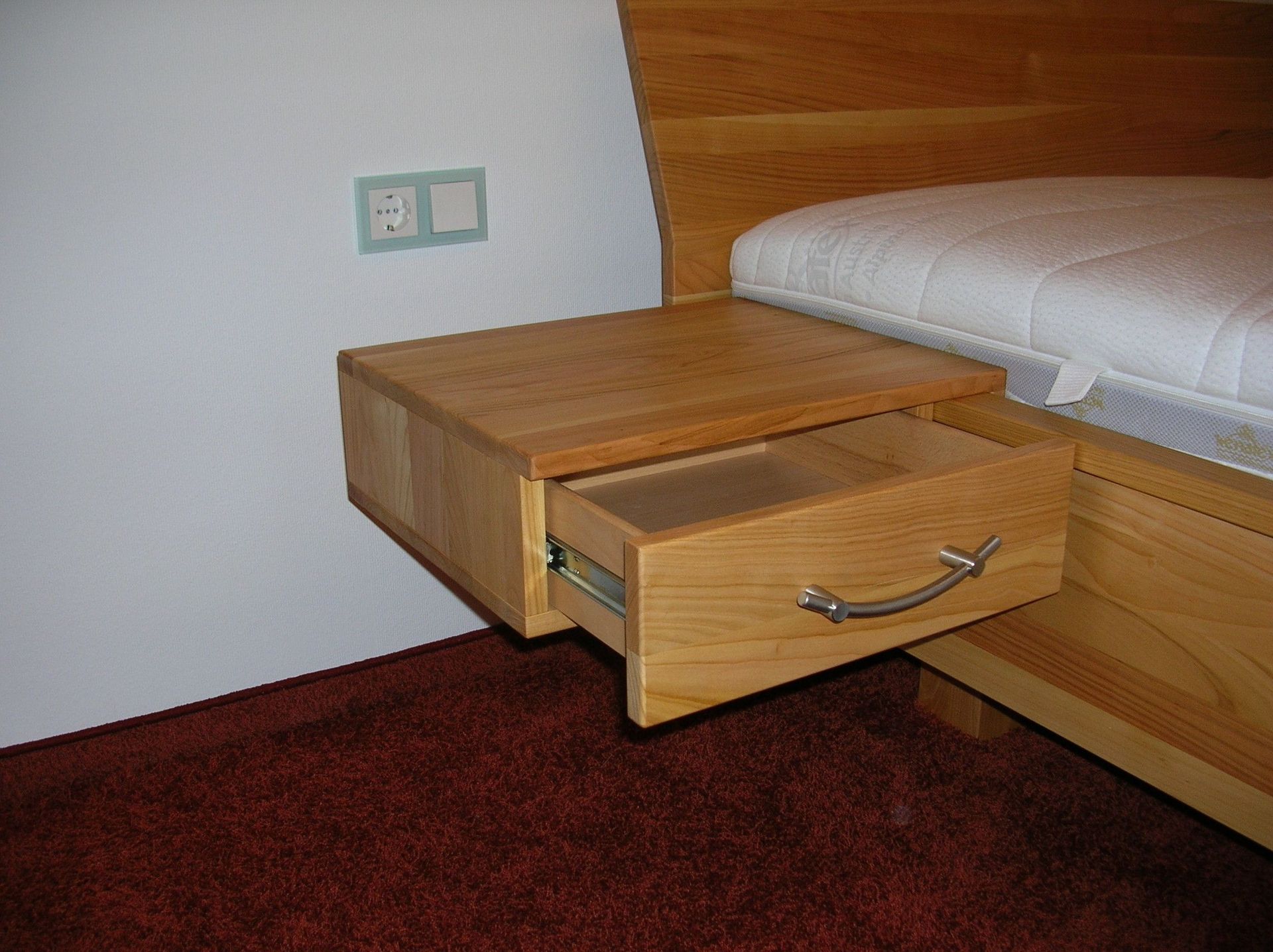 Angebautes Nachtschränkchen am Bett aus Holz