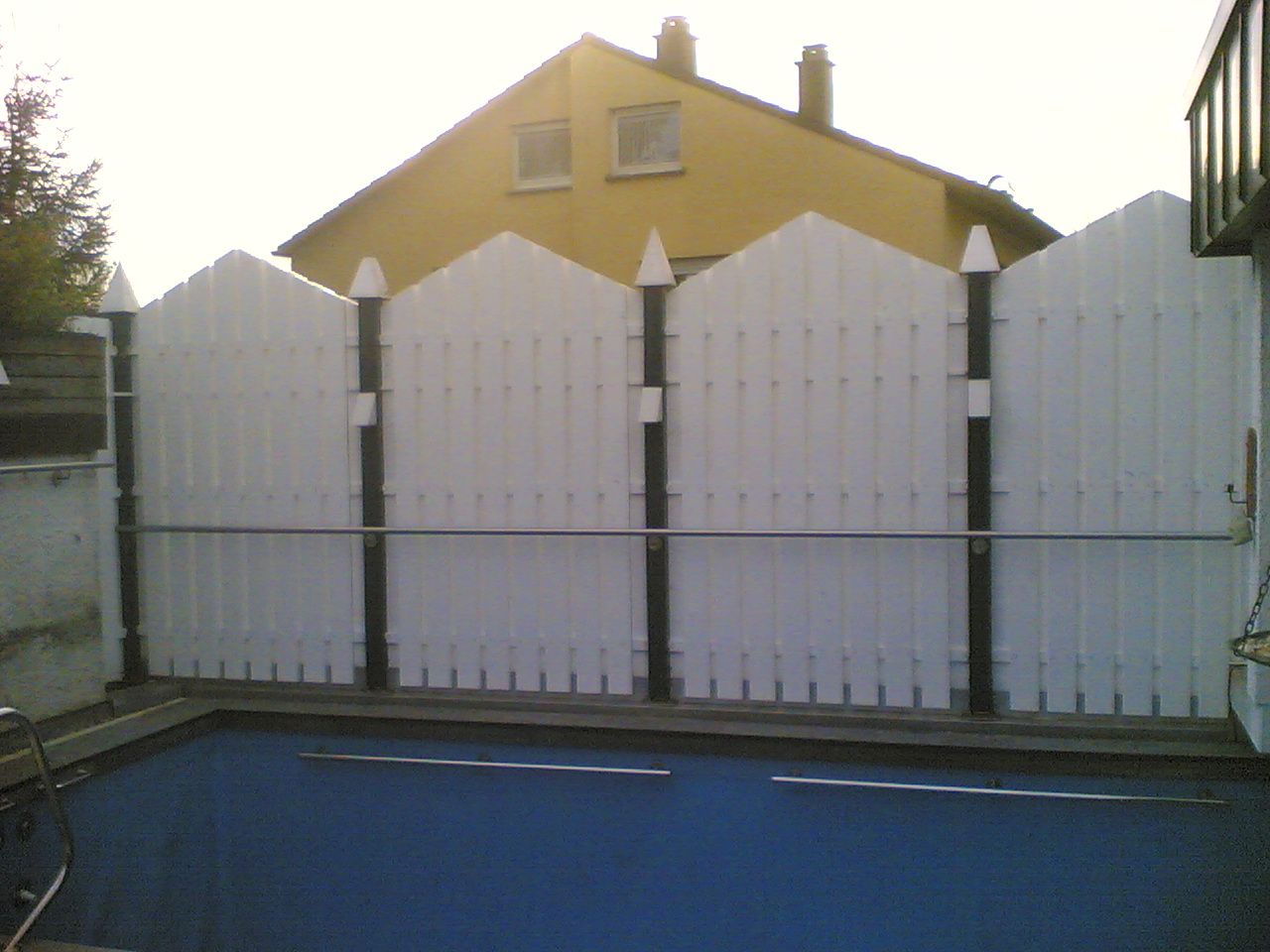 weißer Holzzaun vor einem Wohnhaus