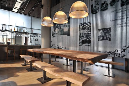 großer Holztisch mit Bänken in einem Raum mit Bar