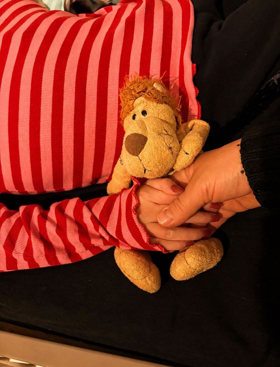 eine Kinderhand hält ein Kuscheltier-Affen und zeitgleich eine erwachsene Hand