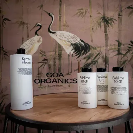 Productos para el cabello sobre una mesa con fondo floral, destacando las botellas de Keratin Infusion y Sublime 10-31.