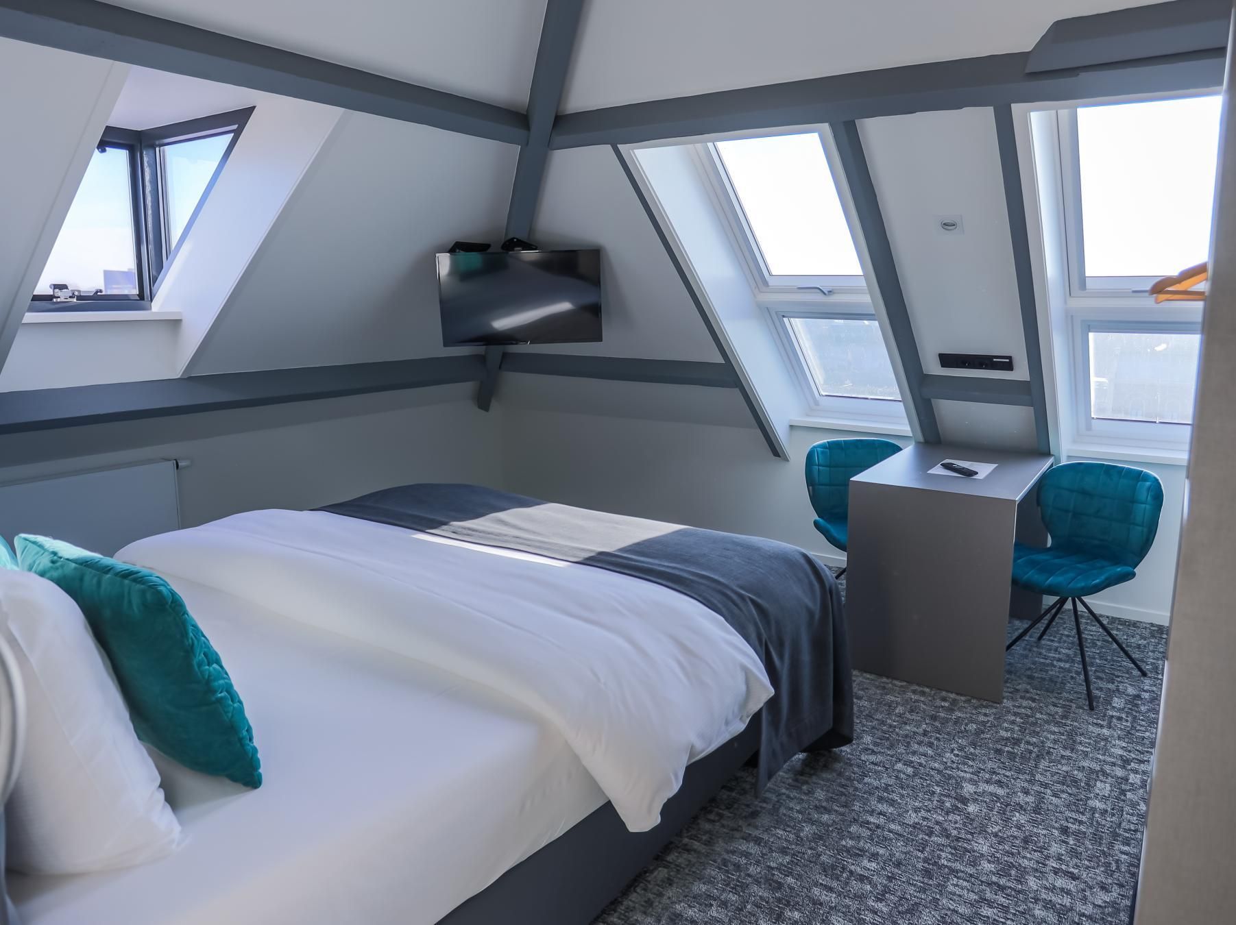 A hotel room with a bed , desk and chairs