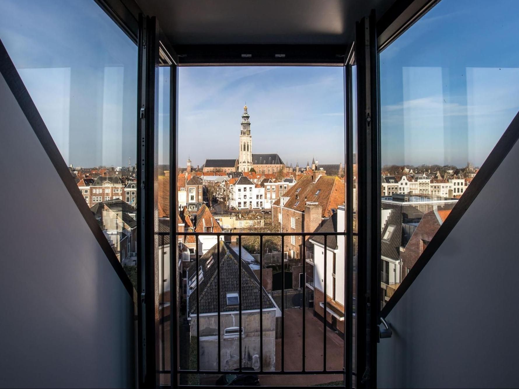 A view of a city from a balcony with a clock tower in the background.