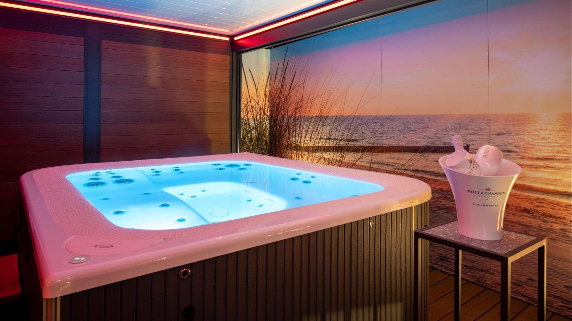A hot tub is sitting in a room with a picture of the ocean on the wall.