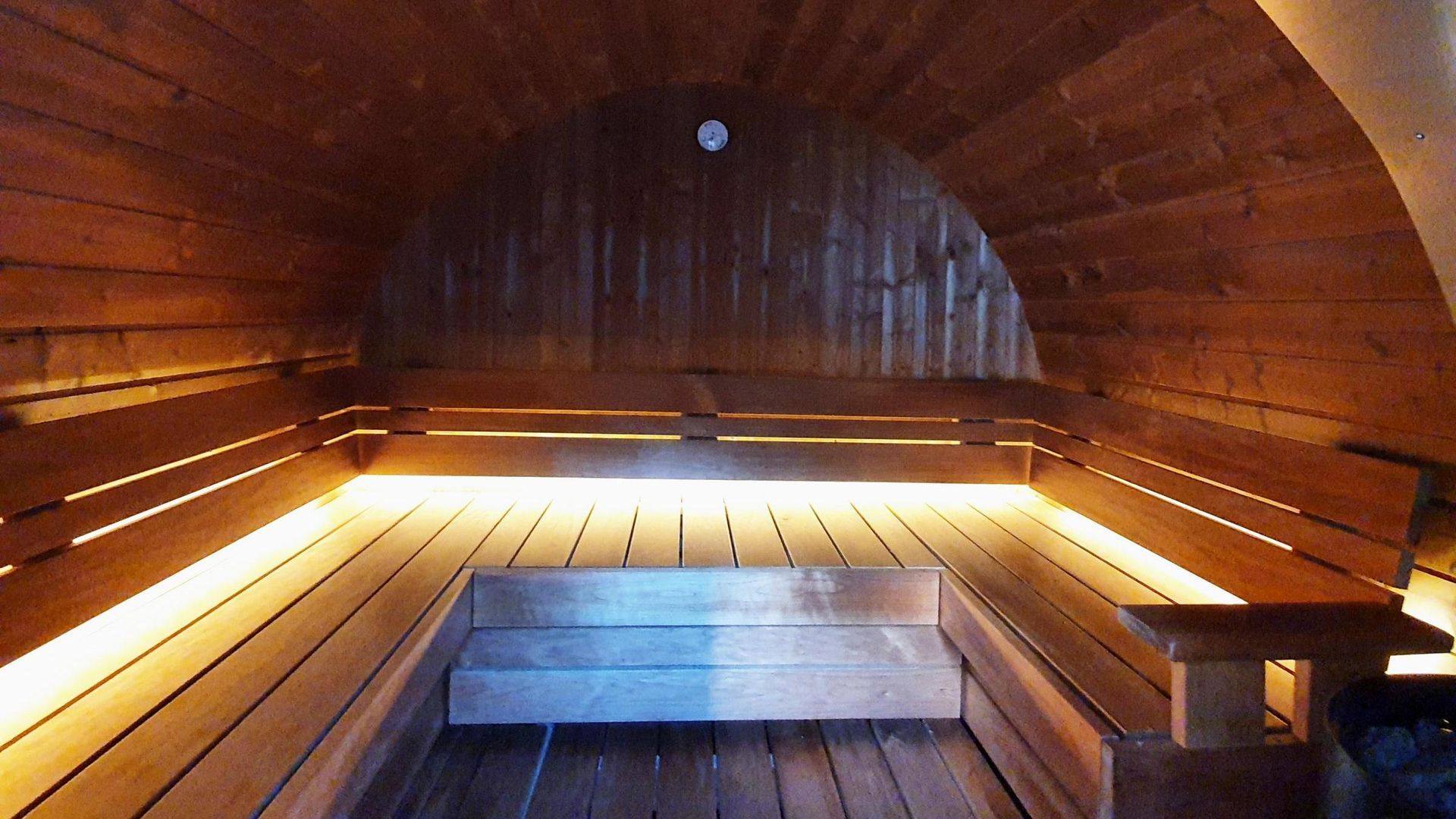 A wooden sauna with lights on the walls and benches
