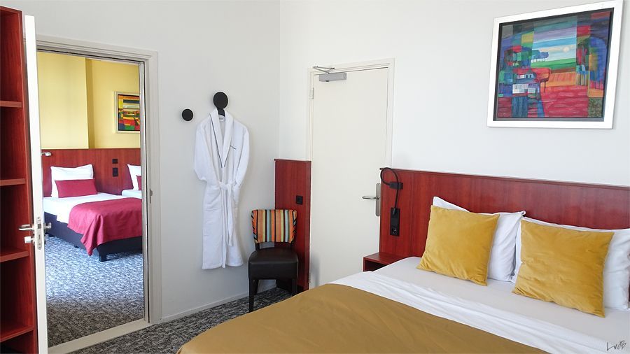 A hotel room with two beds and a painting on the wall.