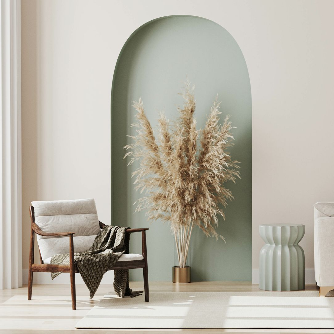 Une pièce aux tons neutres avec une chaise, des herbes de la pampa et une table d'appoint.