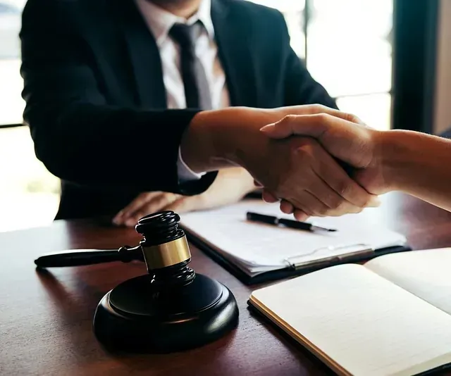 Un hombre con traje y corbata le estrecha la mano a una mujer.