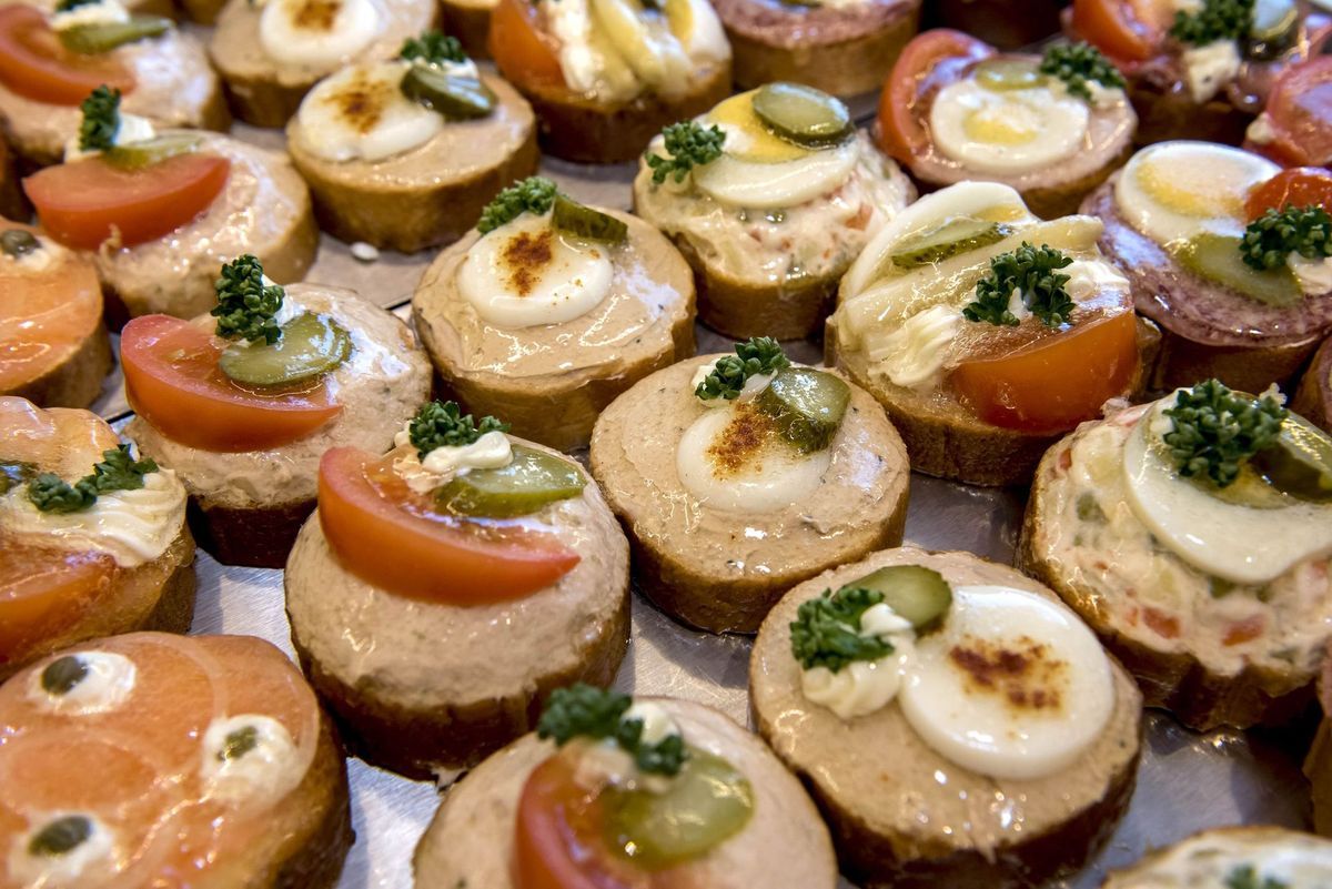 Gros plan de nombreux hors-d'œuvre colorés et assortis sur du pain, certains avec de la tomate, des œufs ou du saumon.
