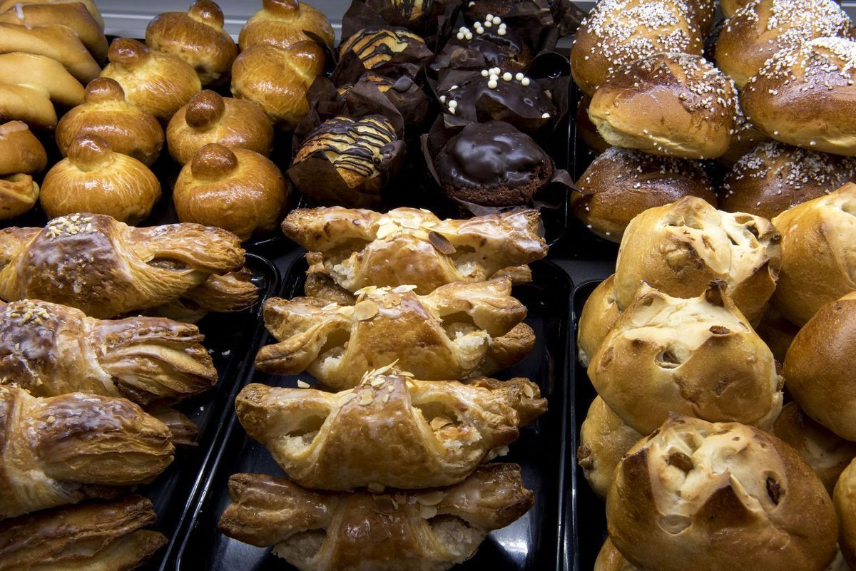 Présentoir de pâtisseries diverses : brioches, muffins au chocolat et viennoiseries sur un plateau noir.