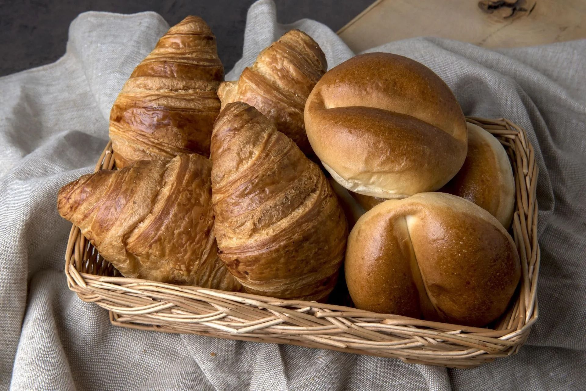 Panier de croissants et petits pains sur une nappe en lin.