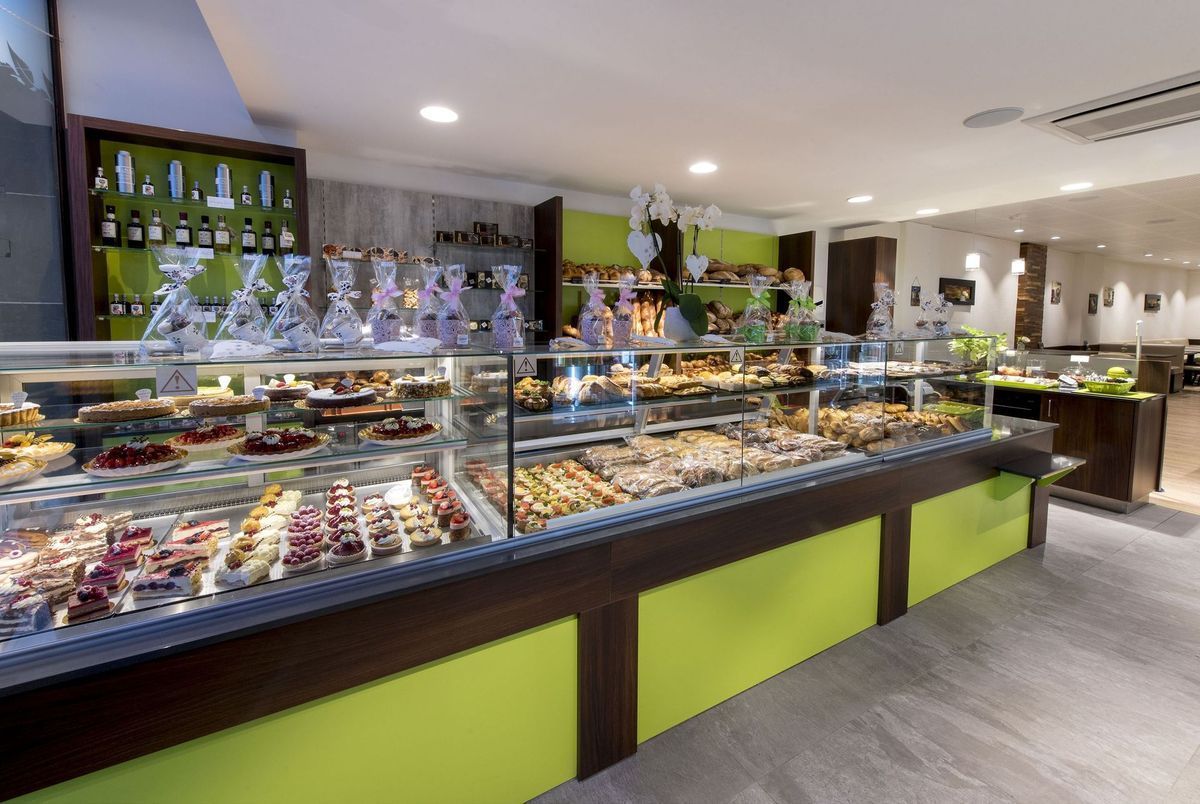 Vitrine de boulangerie remplie de pâtisseries et de desserts, accents vert citron et marron.