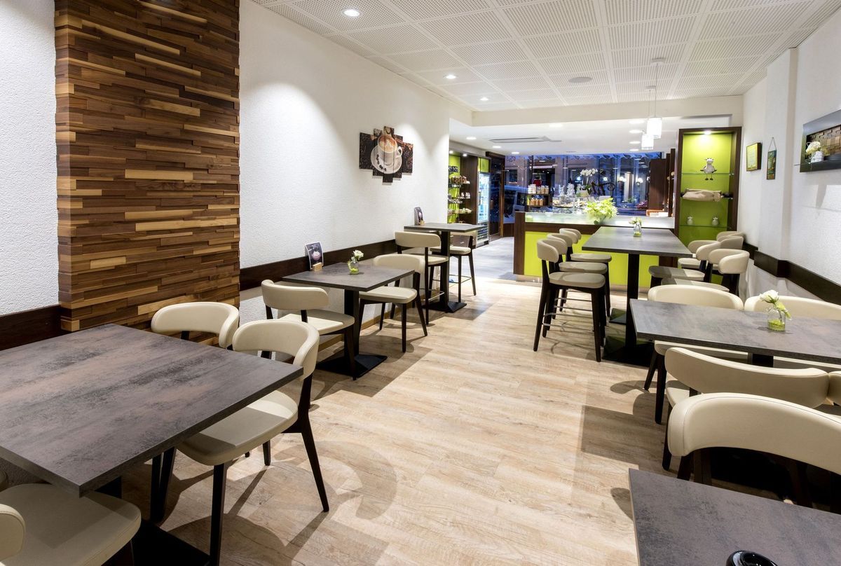 Intérieur d'un café moderne avec des tables, des chaises et un mur d'accent en bois.