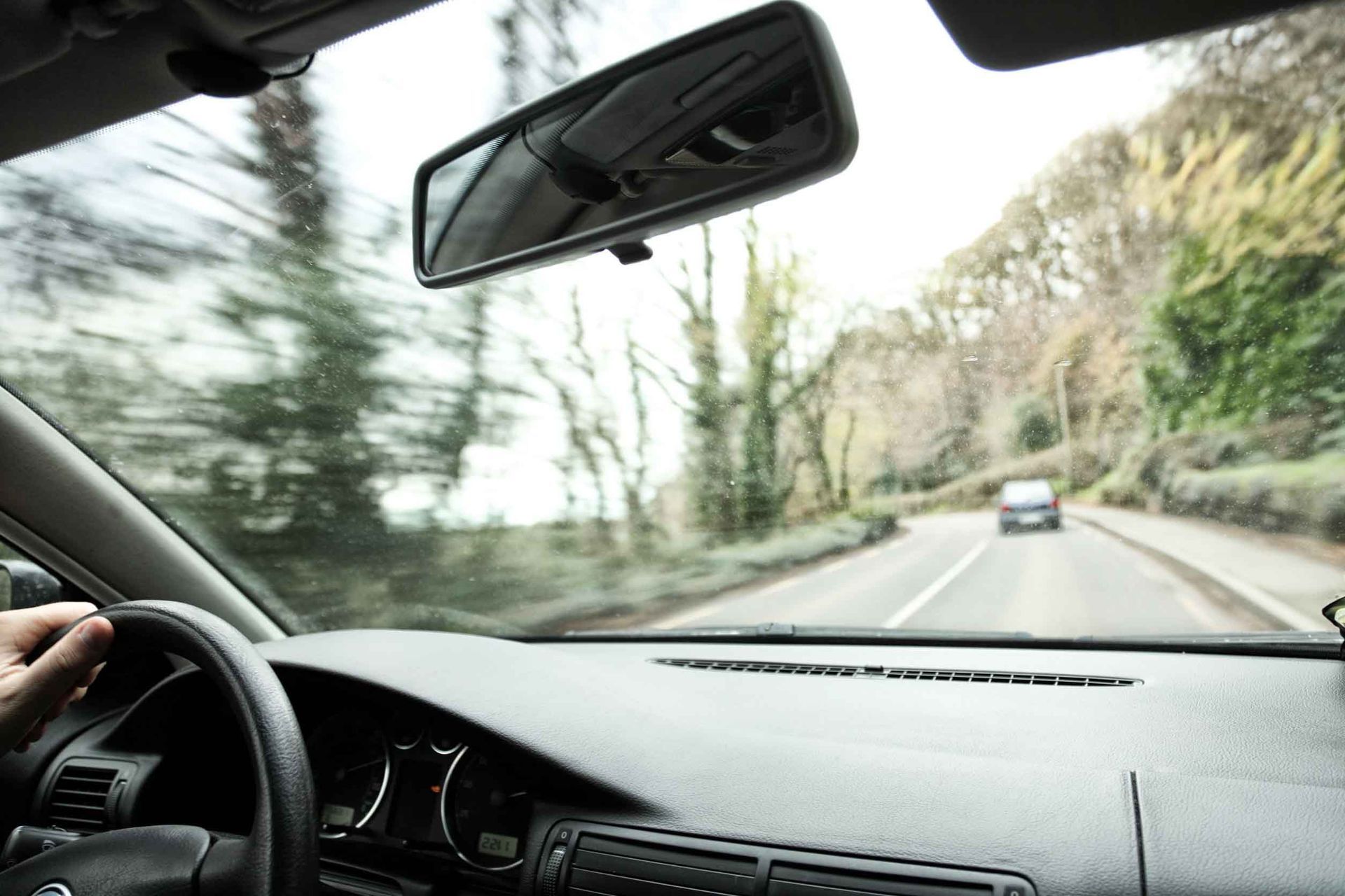 Conducir por una carretera sinuosa a través de una zona boscosa, visto desde el interior de un coche.