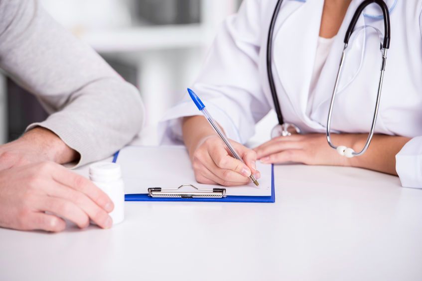 Un médico toma notas en un portapapeles durante una consulta médica en un escritorio.