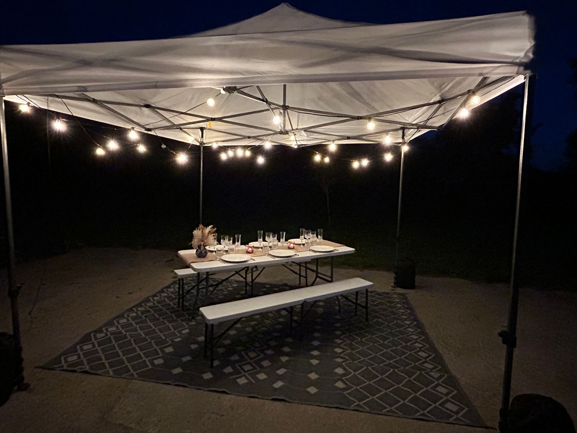Auvent décoré d'une guirlande lumineuse et table posée sur un tapis
