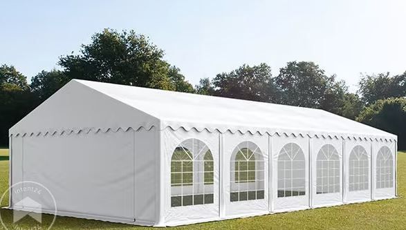 Tente d'évènement blanche avec fenêtres cintrées sur une pelouse herbeuse, journée ensoleillée.