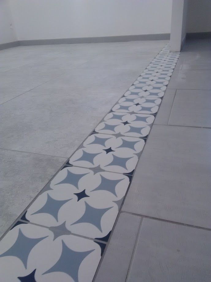 Sol carrelé vide avec une frise décorative à motifs gris et blancs