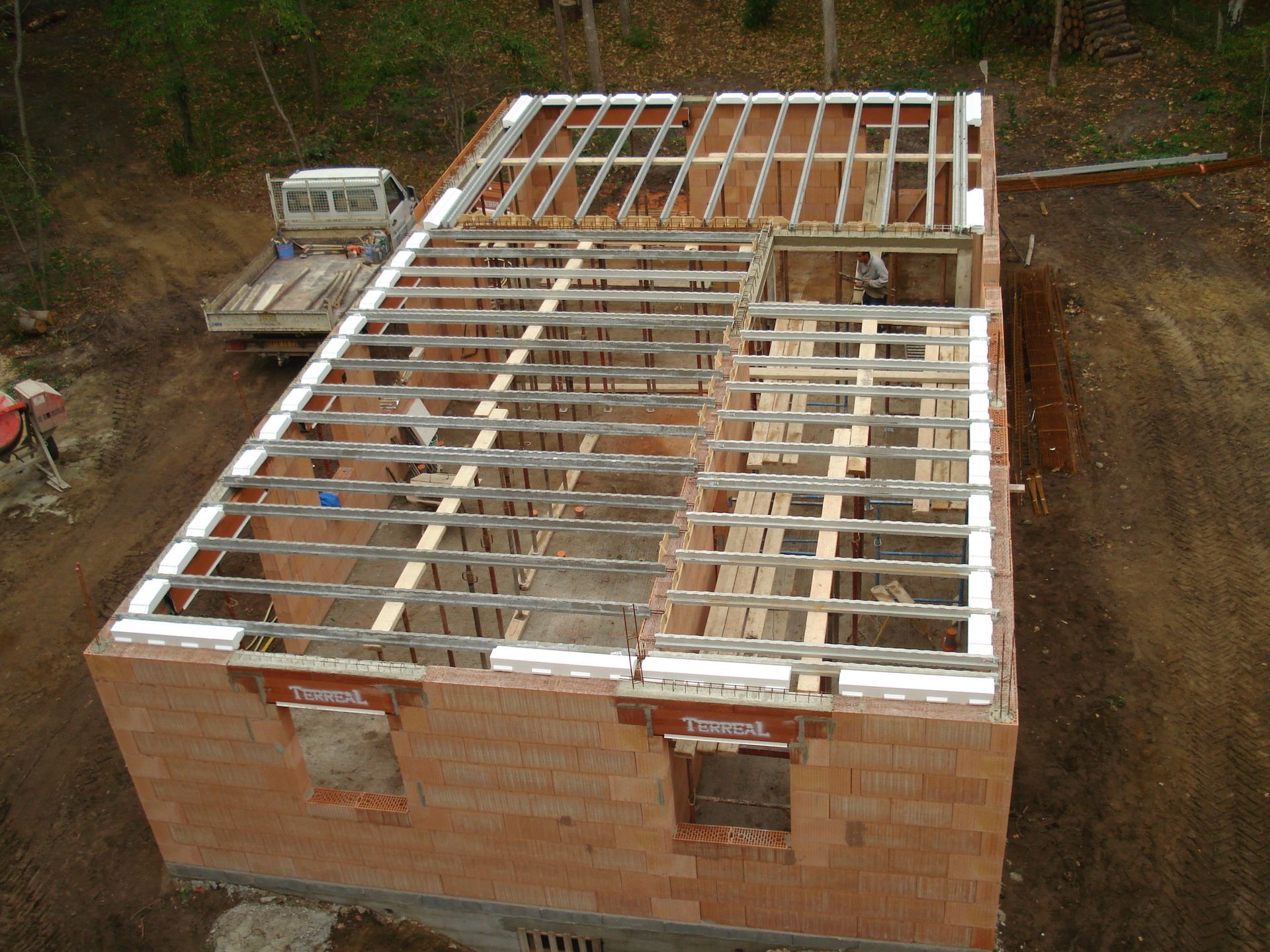 Maison en briques partiellement construite avec charpente apparente sur un chantier