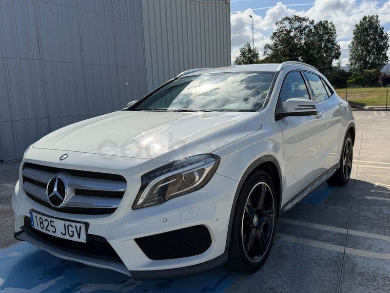 Un SUV Mercedes blanco estacionado frente a un edificio en un día soleado.