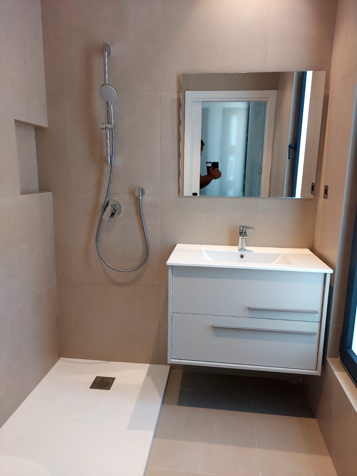 Un baño con lavabo, ducha y espejo.