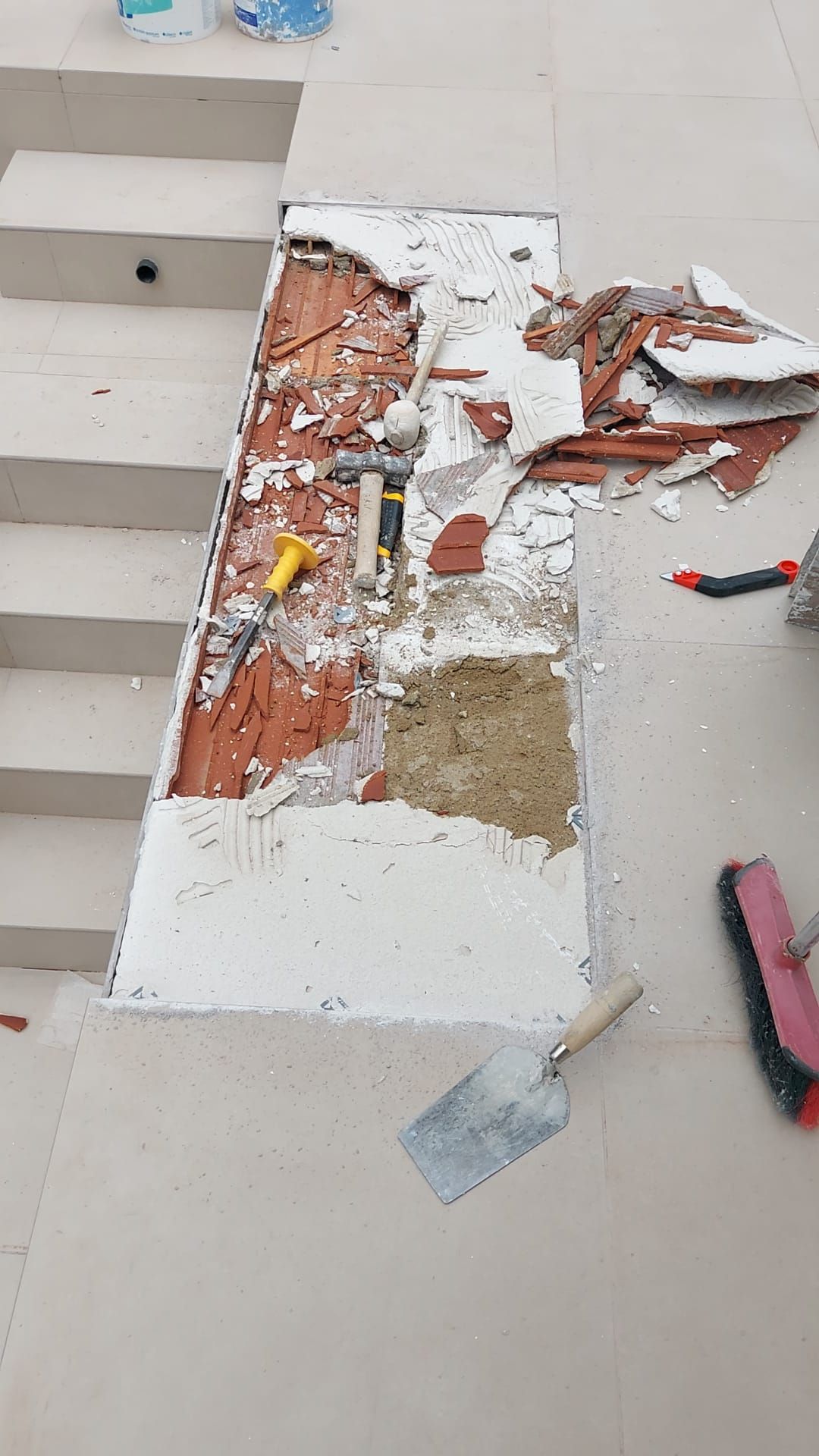 Una persona está trabajando en una escalera con herramientas en el suelo.