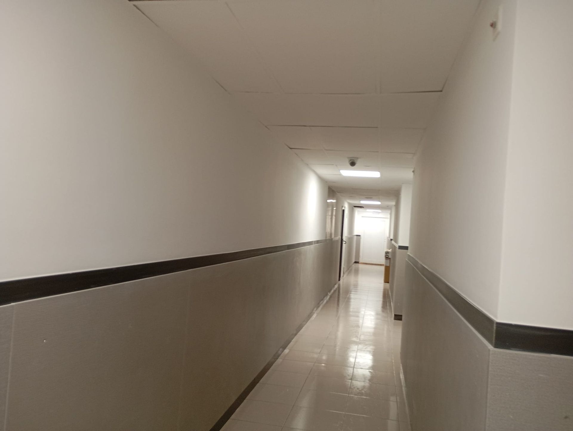 Un largo pasillo con paredes blancas y molduras negras.