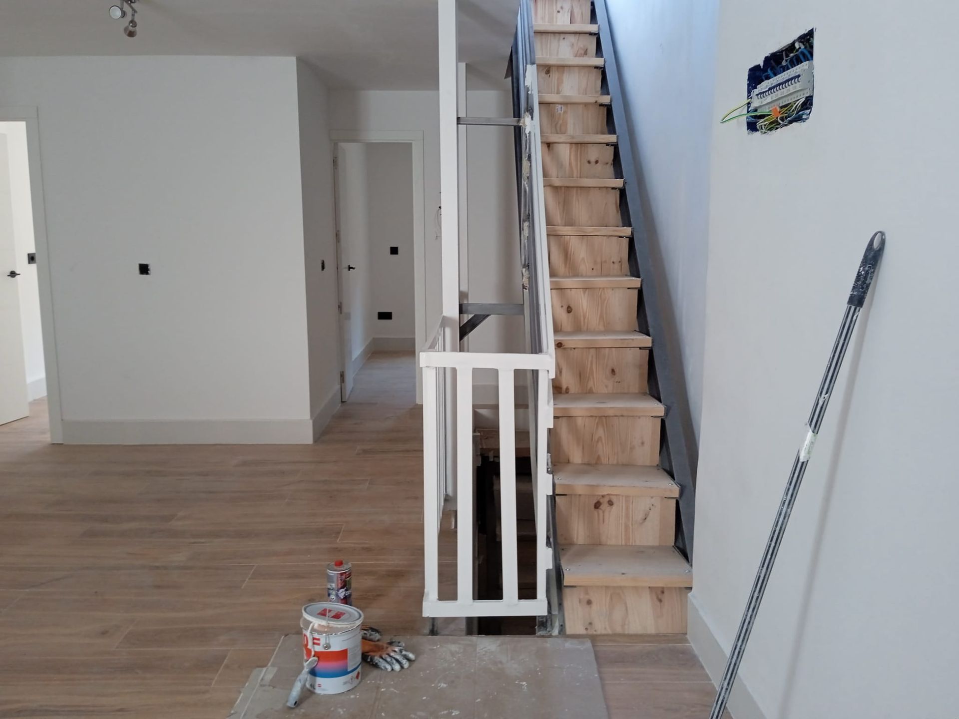Una habitación vacía con una escalera y un cubo de pintura.