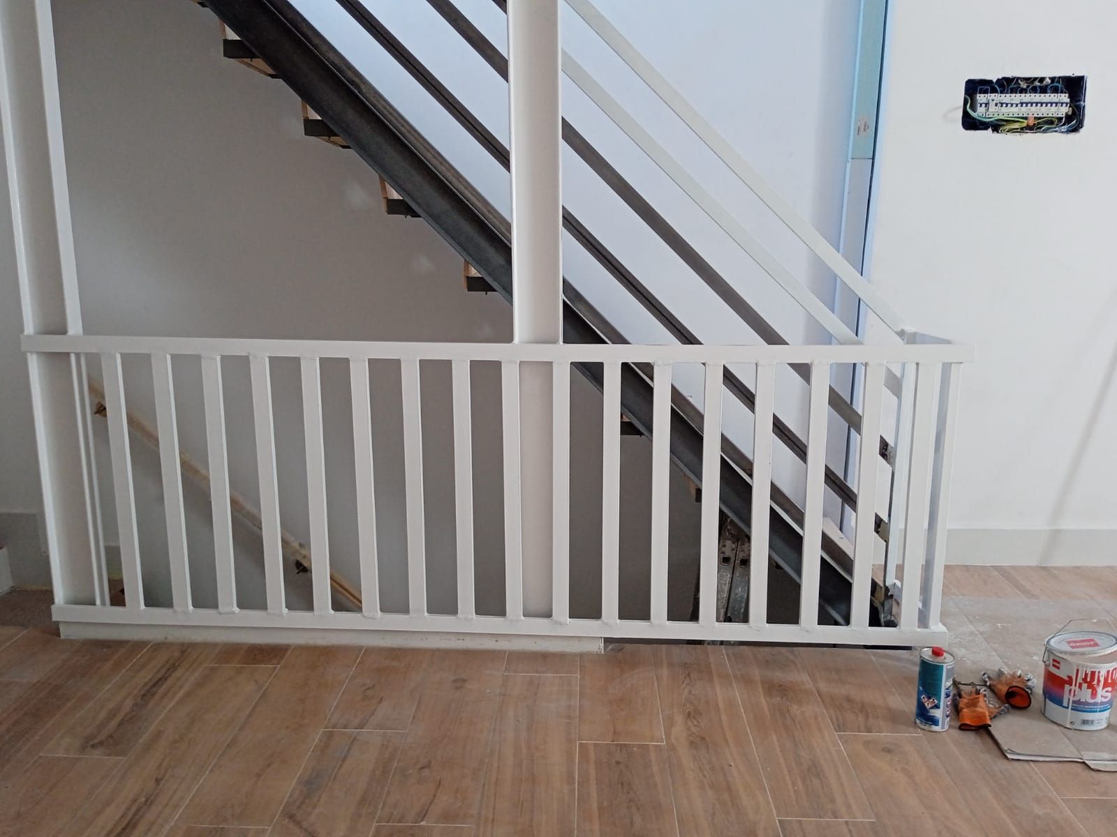Una barandilla blanca está al lado de una escalera en una habitación.